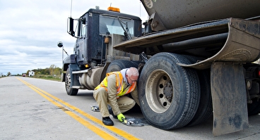 Truck-weight instructor placing a scale under a semi truck tire