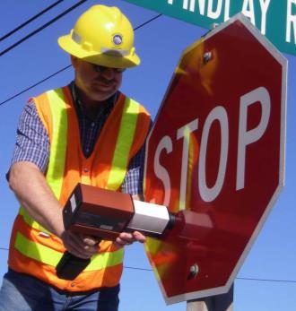 Worker testing a stop sign for reflectivity