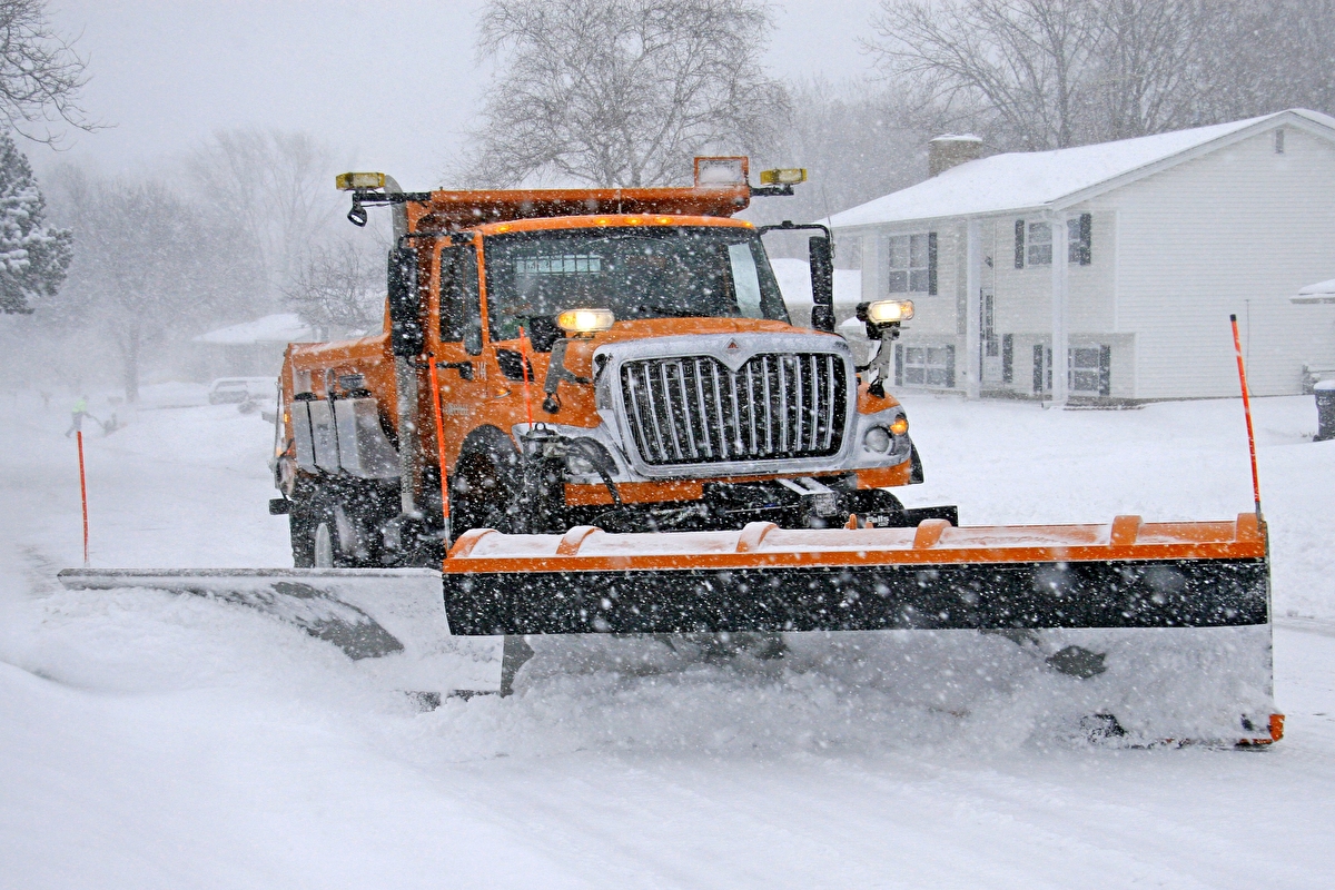 A snowplow clears a road during a storm.