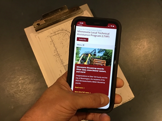Hand holding a mobile device showing the new LTAP website