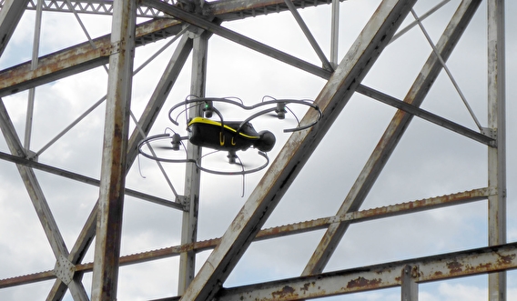 A drone flying close to a metal bridge structure