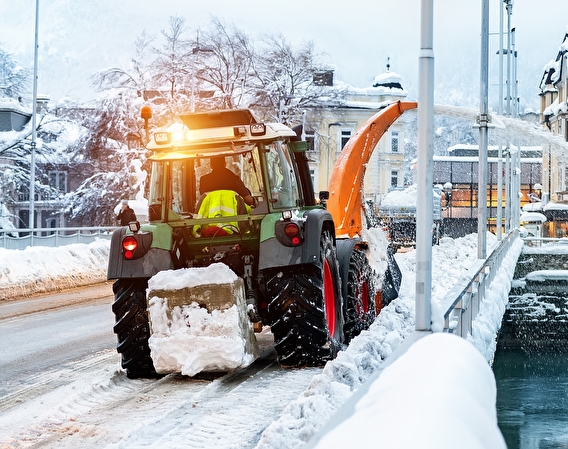 Snowblower clearing snow from a bridge in a city