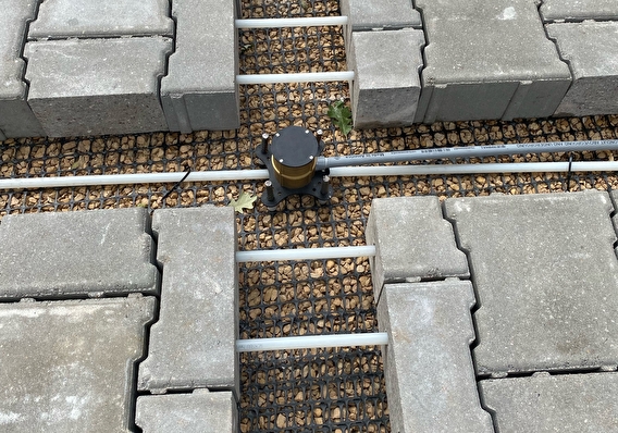 close-up photograph of heated pavement blocks and cable pipes