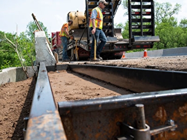 Workers installing a bridge approach transition curb