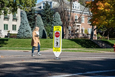 Woman crossing at a crosswalk with a mid-road sign
