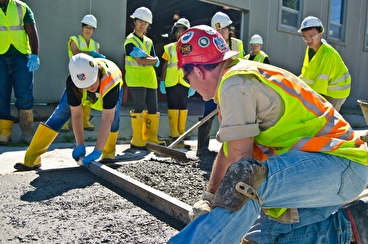Workers wearing PPE working with freshly poured concrete