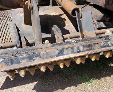 A close-up of the belly scratcher attachment on a gravel road.